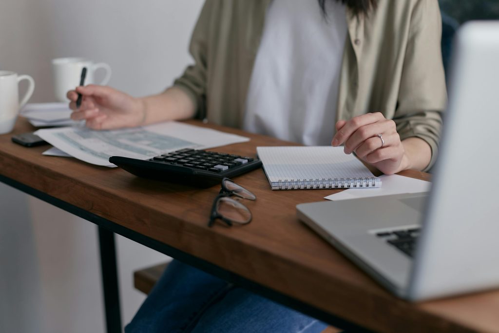 Closeup of person working at a desk with papers and a calculator