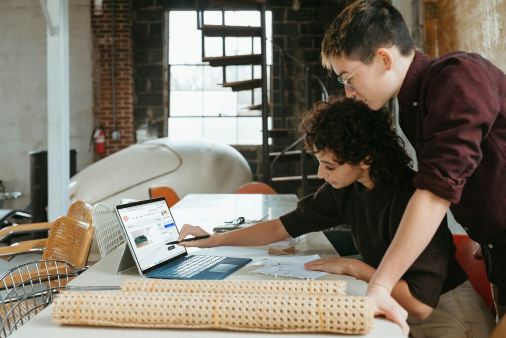 Two boys using a laptop on a couch, focused on the screen.