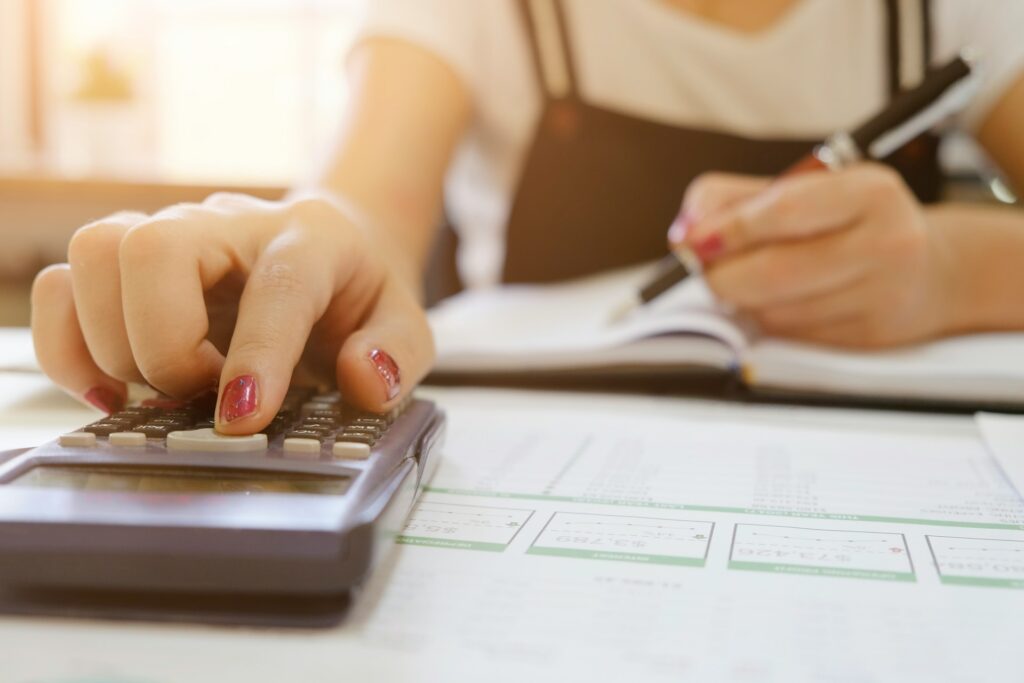 Person using calculator while writing notes on paper.